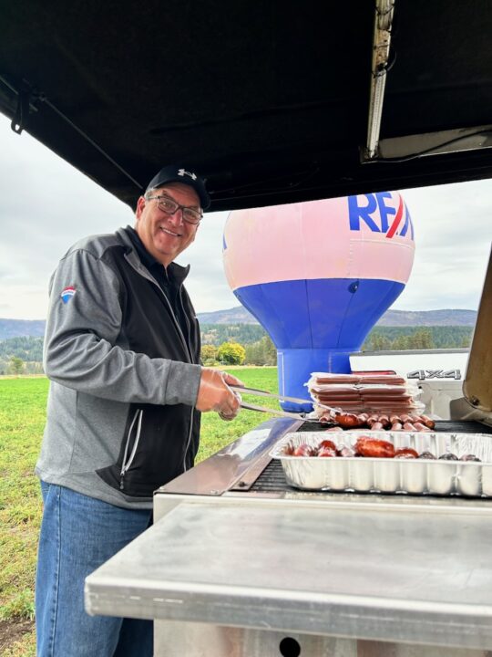 RE/MAX Vernon Salt Fowler serving hot dogs during Pumpkin Patch Day.